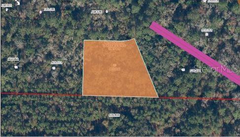 This is an aerial map showing a highlighted plot of land surrounded by wooded areas — 121 CORBINA WAY W, FLORAHOME, FL