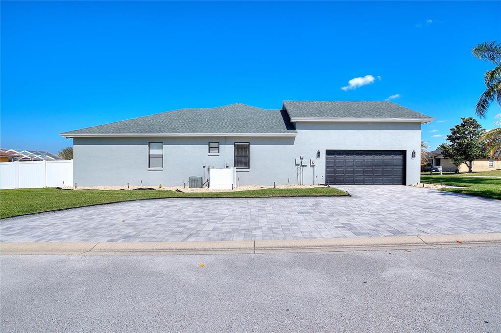 A grassy backyard features a white vinyl privacy fence and a small paved patio area — 2687 BROOKSIDE BLUFF LOOP, LAKELAND, FL