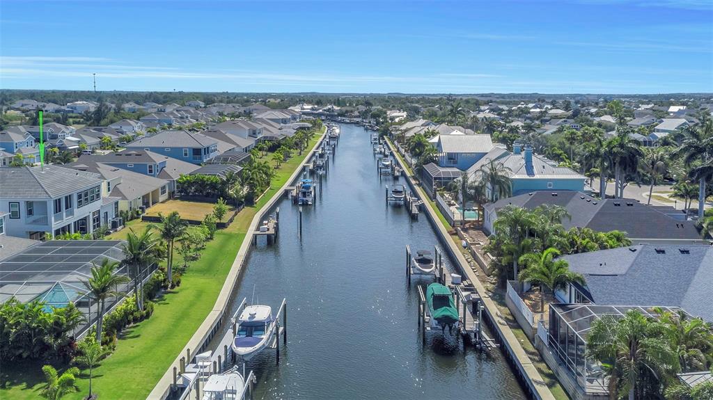 An aerial view shows a canal lined with residential houses, private docks, and moored boats — 1016 SIGNET DRIVE, APOLLO BEACH, FL