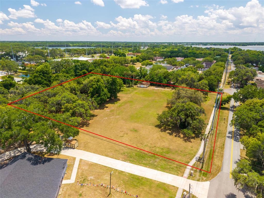 An aerial view shows a large, grassy, rectangular lot outlined in red next to a road — 1925 COUNTY ROAD 19A, EUSTIS, FL