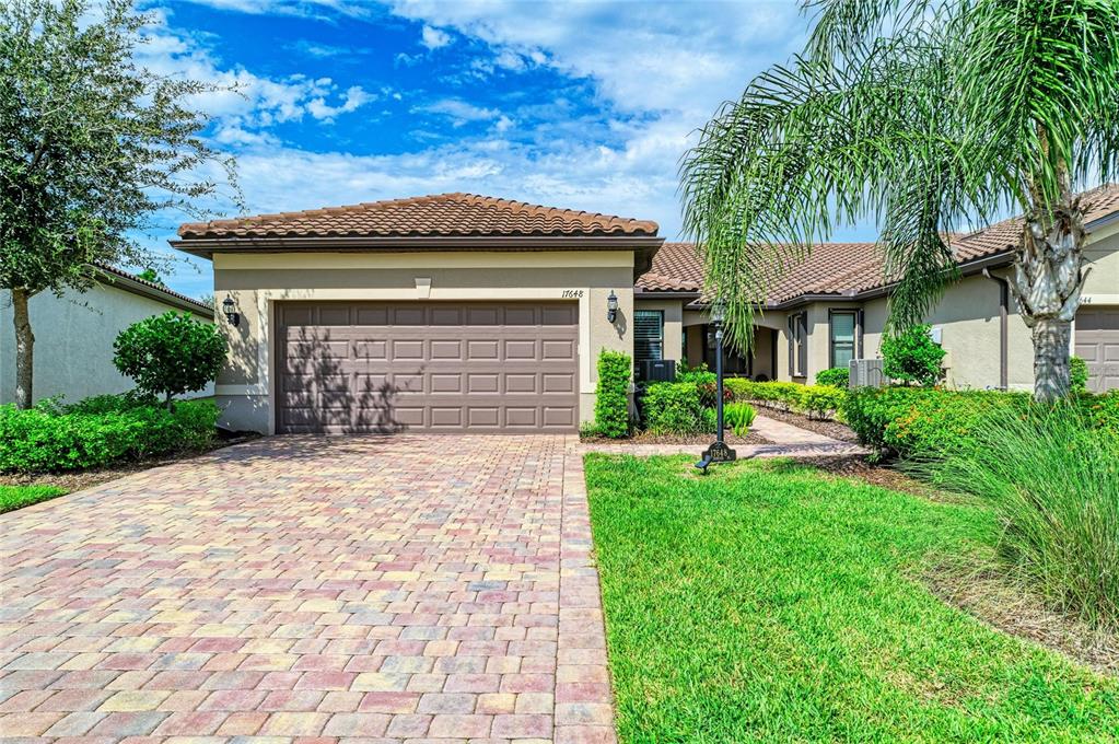 A single-story house with a paved driveway, a two-car garage, and a landscaped front yard — 17648 NORTHWOOD PLACE, LAKEWOOD RANCH, FL