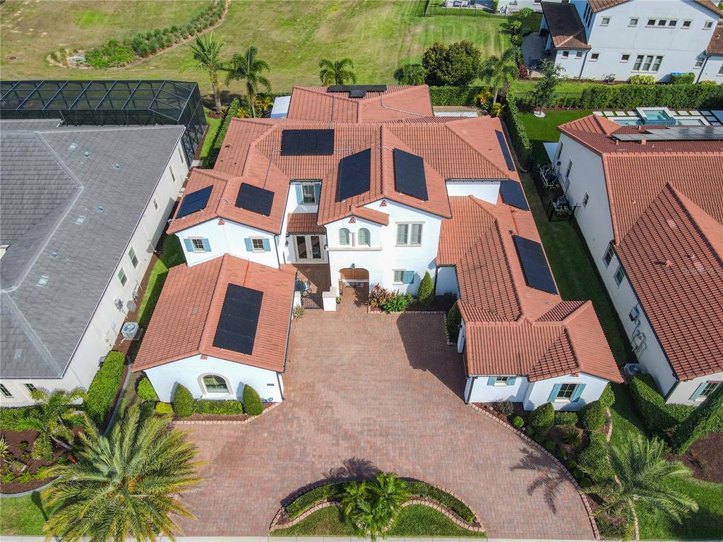 An aerial view shows a white house with a red tile roof and solar panels — 15680 PANTHER LAKE DRIVE, WINTER GARDEN, FL