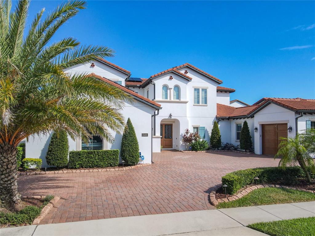 A two-story white stucco house with a red tile roof and a brick paver driveway — 15680 PANTHER LAKE DRIVE, WINTER GARDEN, FL