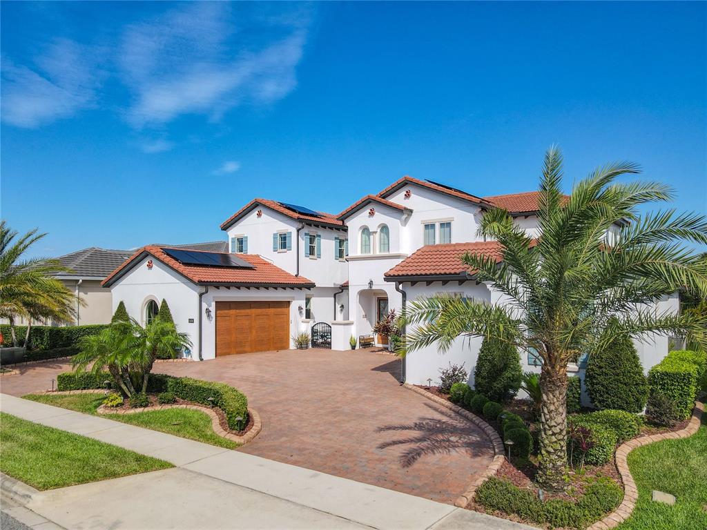 A two-story stucco house with a tile roof, solar panels, and a paved driveway — 15680 PANTHER LAKE DRIVE, WINTER GARDEN, FL