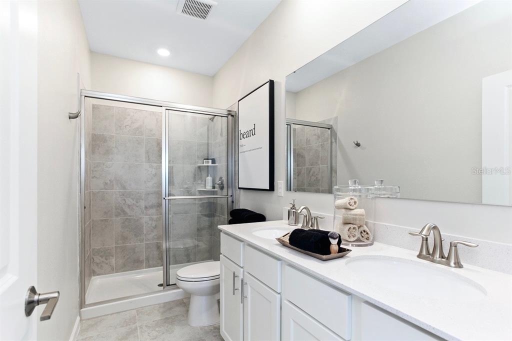 A bathroom features a double vanity, a glass-enclosed shower, and light-colored tile flooring — 9818 RED EAGLE DRIVE, ORLANDO, FL