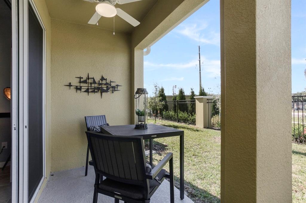 A covered patio features a small dining set, a wall sculpture, and a ceiling fan — 9818 RED EAGLE DRIVE, ORLANDO, FL