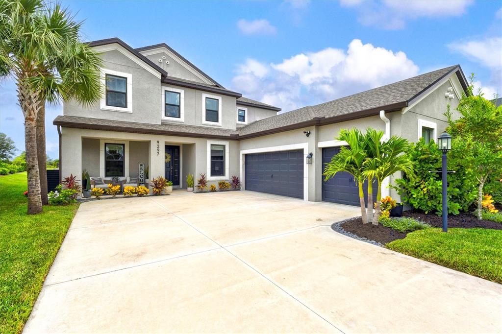 A two-car garage with dark paneled doors and a concrete driveway in front of a house — 9297 TEQUILA SUNRISE DRIVE, SARASOTA, FL