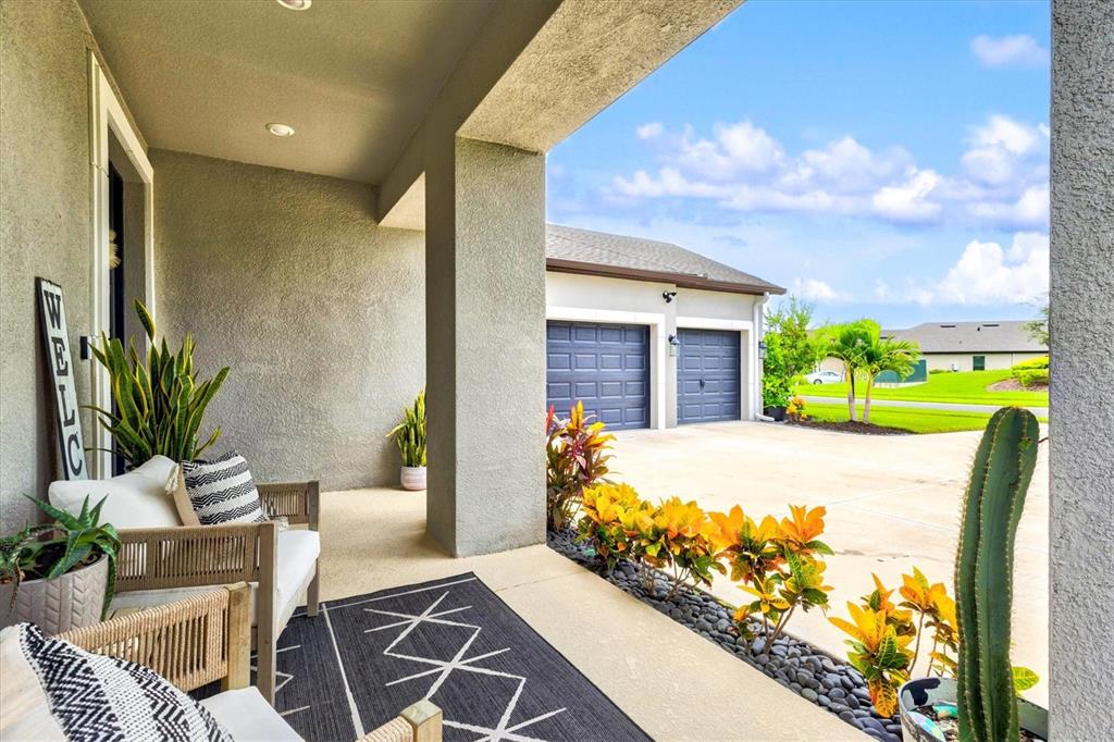 A bright foyer features light wood-look tile flooring, a staircase with white railings, and a door — 9297 TEQUILA SUNRISE DRIVE, SARASOTA, FL