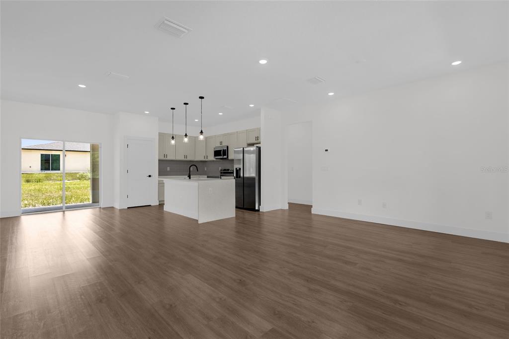 A modern open-concept kitchen with white cabinetry and a center island overlooks a living area — 7295 N GLENRIDGE CIRCLE, CITRUS SPRINGS, FL