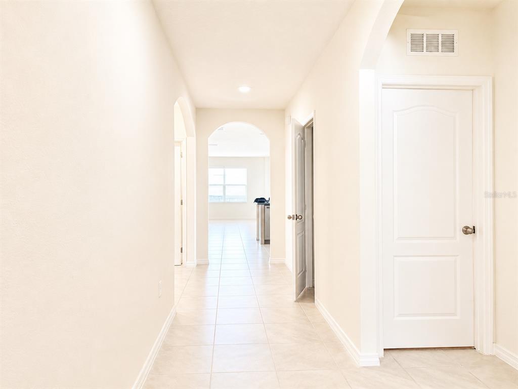 A hallway with light-colored tile flooring leads toward an arched opening into another room — 2132 SILVER BROOK WAY, DAVENPORT, FL
