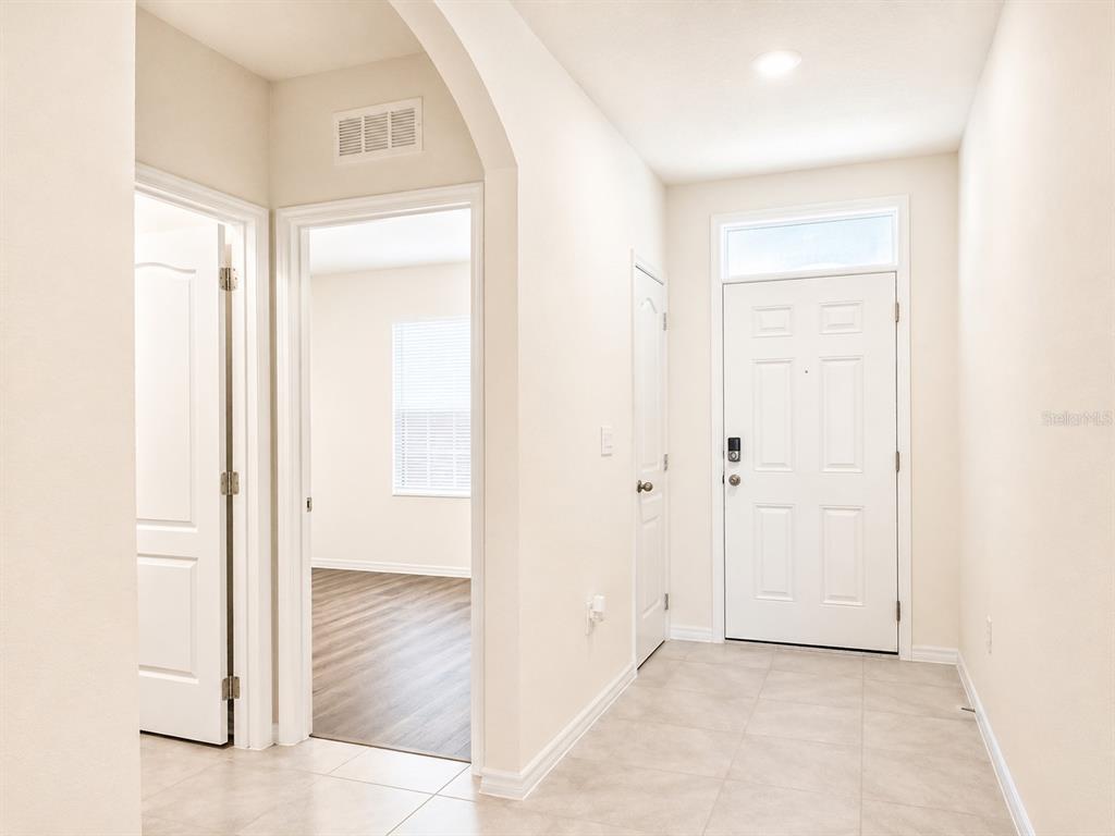 An entryway with tile flooring, a white front door, and an arched doorway to a room — 2132 SILVER BROOK WAY, DAVENPORT, FL