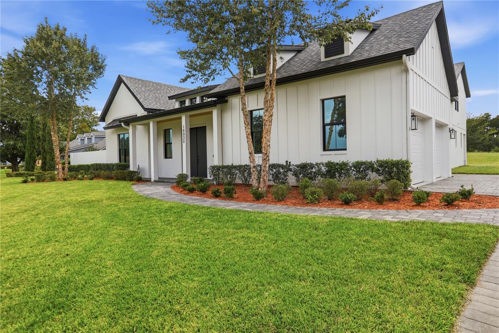 A white modern farmhouse with black trim, a paved walkway, and a green lawn — 16930 WINTER ROAD, MONTVERDE, FL