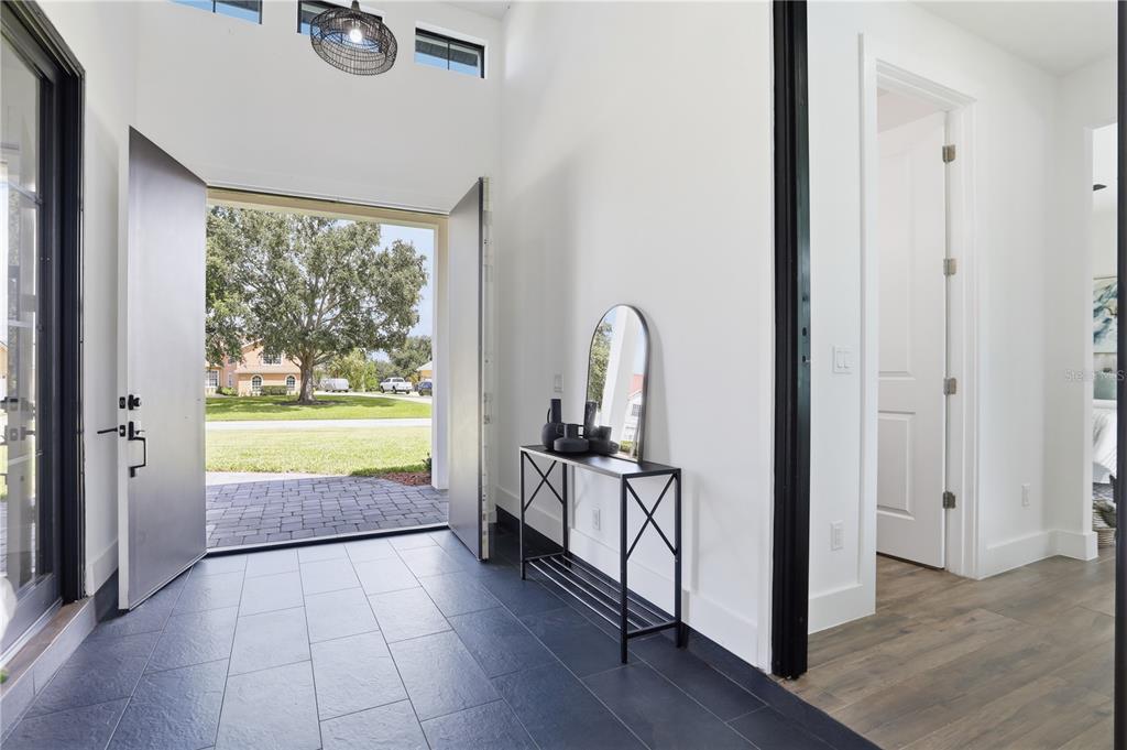 An entryway with dark tile flooring, a black console table, and an open double door — 16930 WINTER ROAD, MONTVERDE, FL