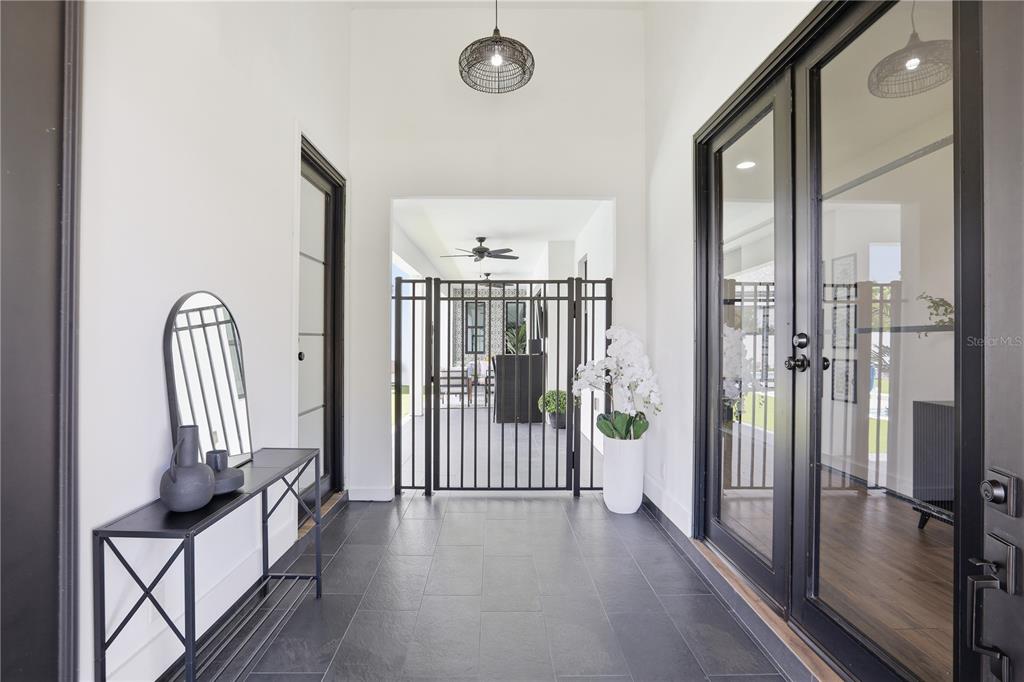 A covered entryway features dark tile flooring, a black metal gate, and glass-paned double doors — 16930 WINTER ROAD, MONTVERDE, FL