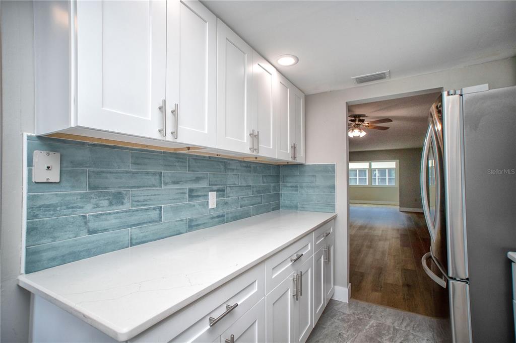 A kitchen features white cabinets, a light-colored countertop, and a blue subway tile backsplash — 5840 30TH AVENUE S UNIT 202, GULFPORT, FL
