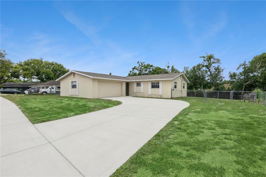 A single-story house with a beige exterior, a two-car garage, and a concrete driveway — 1912 SAXON BOULEVARD, DELTONA, FL