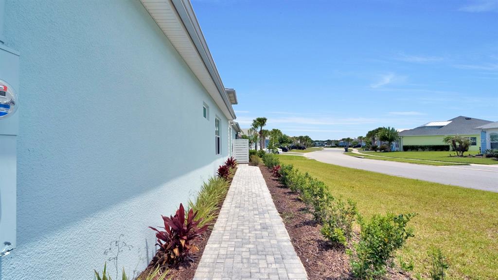 A paved walkway runs alongside the light blue exterior wall of a house — 202 SUMMERTIME PLACE, DAYTONA BEACH, FL