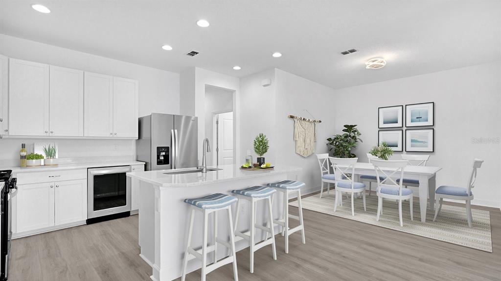 A modern kitchen and dining area feature white cabinets, stainless steel appliances, and light flooring — 202 SUMMERTIME PLACE, DAYTONA BEACH, FL
