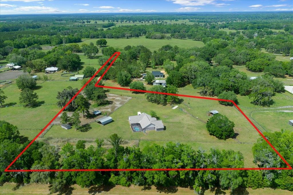 An aerial view shows a house with a pool on a large, fenced rural lot — 13456 W HIGHWAY 318, WILLISTON, FL