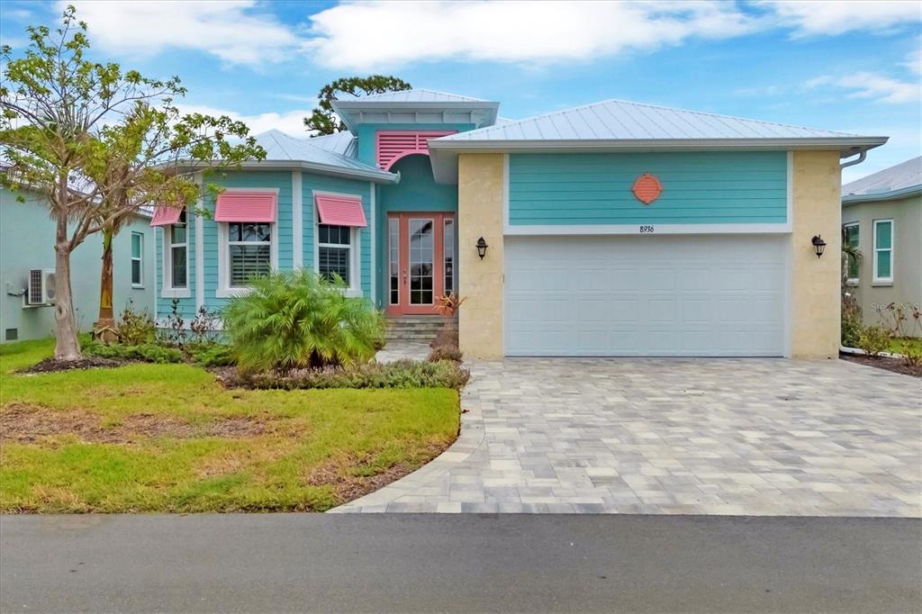 A teal and tan house with a metal roof, pink accents, and a paved driveway — 8936 SCALLOP WAY, PLACIDA, FL