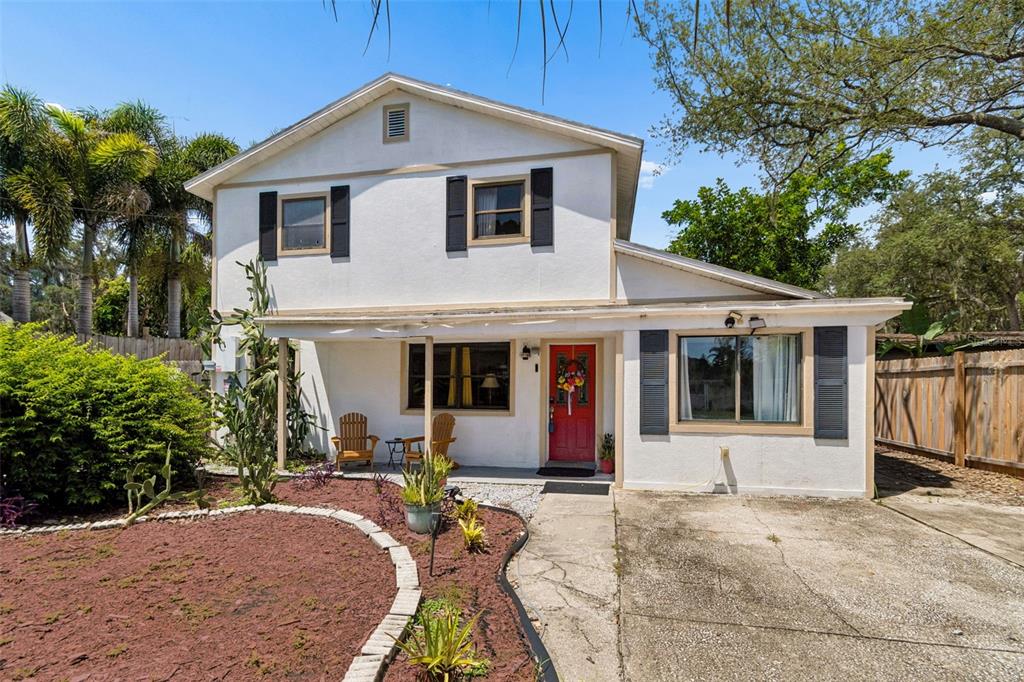A two-story house with white stucco siding, a red front door, and a concrete driveway — 2017 S VILLAGE AVENUE, TAMPA, FL