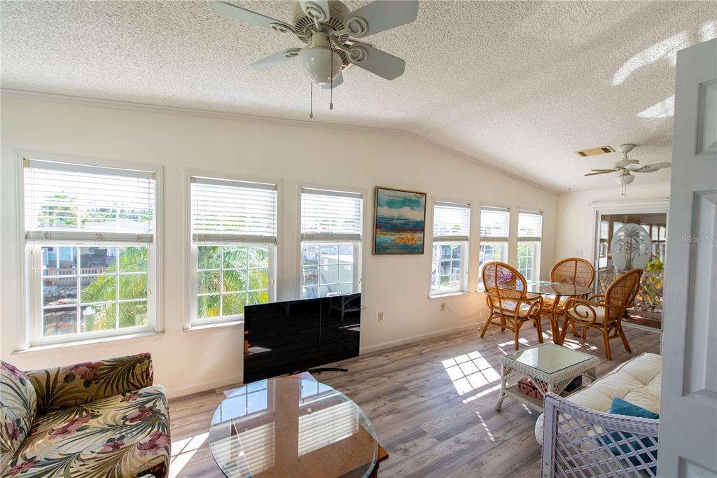 A sunroom features wood-look flooring, multiple windows, two ceiling fans, and wicker furniture — 15 ROTTERDAM DRIVE, PUNTA GORDA, FL