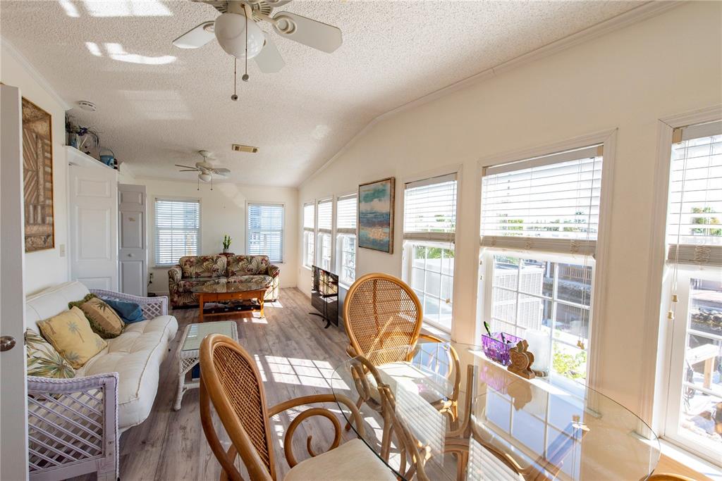 A sunroom features a dining set, a sofa, wood-look flooring, and multiple windows — 15 ROTTERDAM DRIVE, PUNTA GORDA, FL