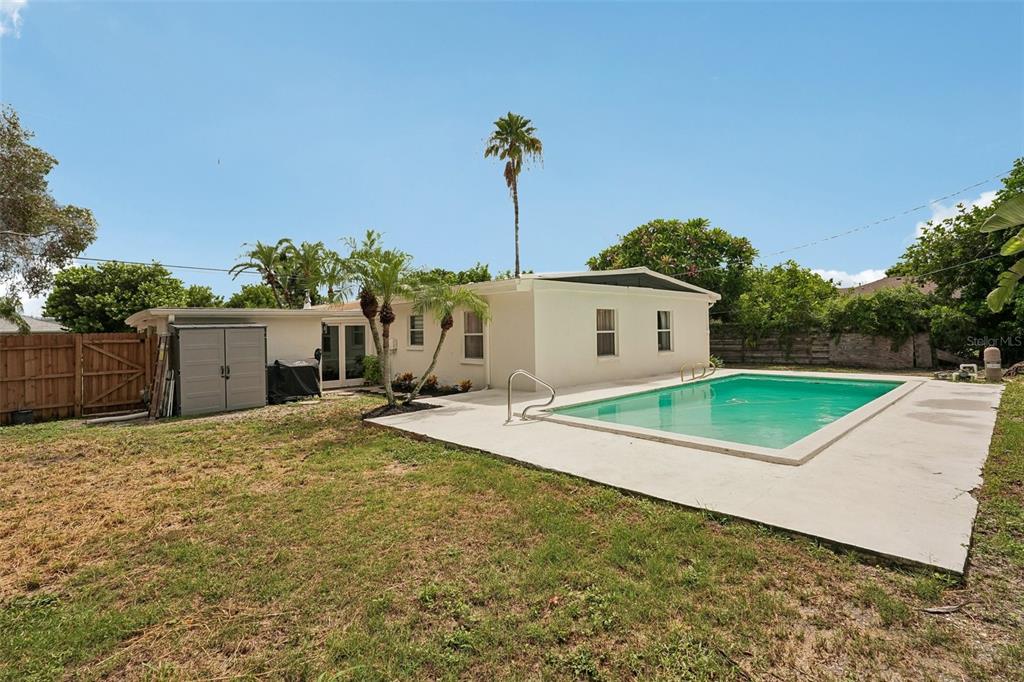 The exterior of a white house features a swimming pool and a small storage shed — 2406 FLORIDA BOULEVARD, BRADENTON, FL