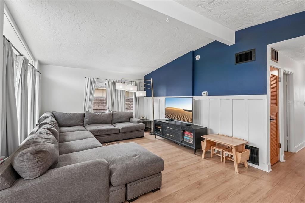A living room features a gray sectional sofa, a television on a stand, and blue walls — 2406 FLORIDA BOULEVARD, BRADENTON, FL