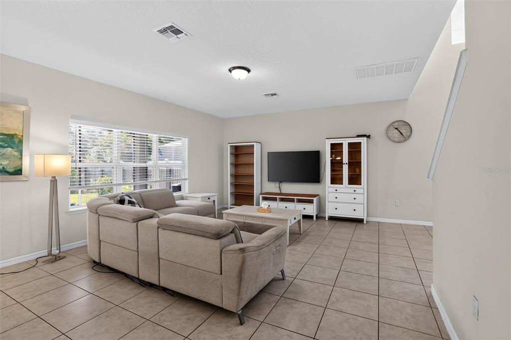 A living room features tile flooring, a sectional sofa, a television, and white cabinetry — 3145 JADE TREE POINT, OVIEDO, FL