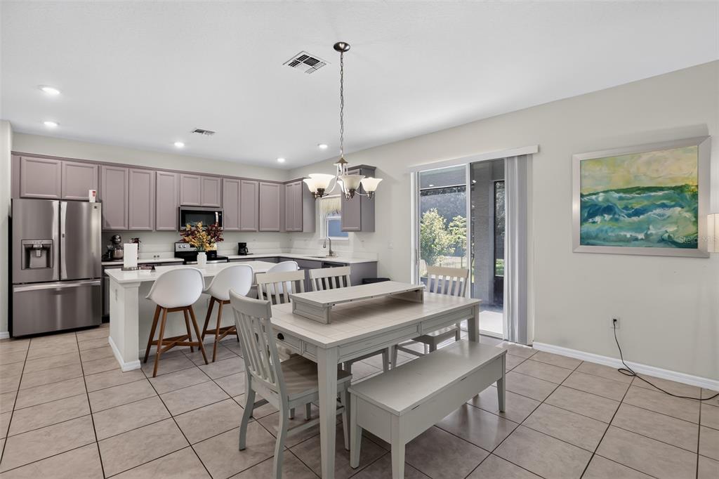 A kitchen and dining area with light-colored cabinets, stainless steel appliances, and tile flooring — 3145 JADE TREE POINT, OVIEDO, FL