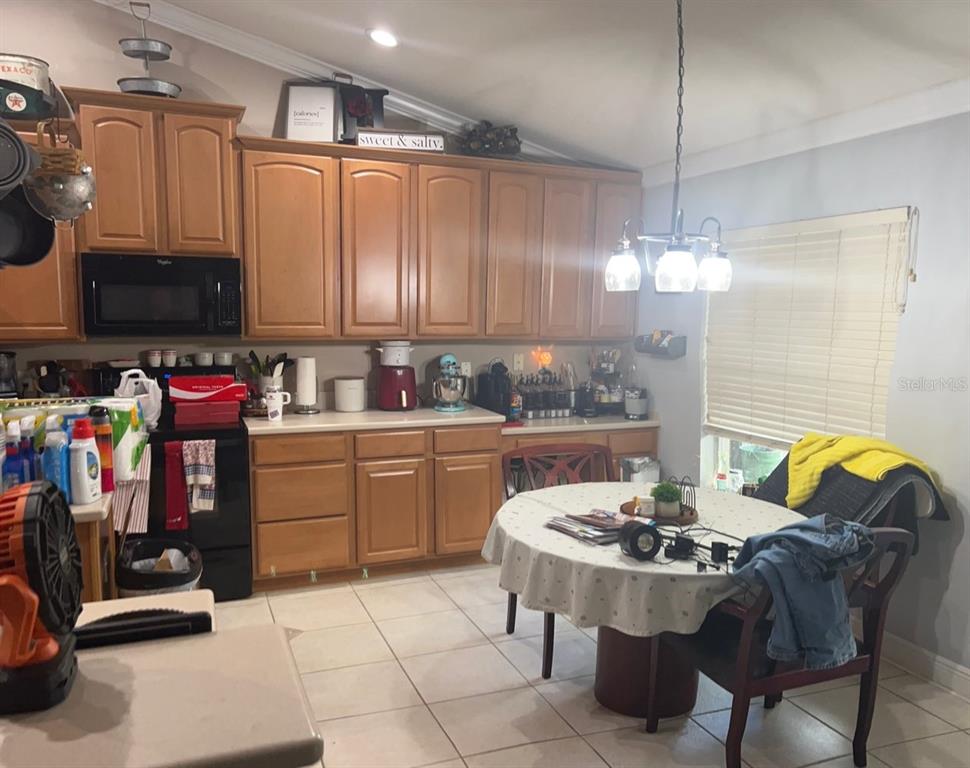 A kitchen with wood cabinets, black appliances, tile flooring, and a round dining table — 5781 AUTUMN CHASE CIRCLE, SANFORD, FL