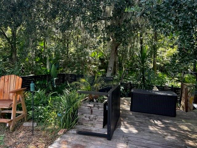 A wooden deck features a chair, a planter box, and a storage bin near trees — 5781 AUTUMN CHASE CIRCLE, SANFORD, FL