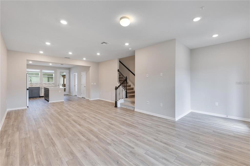 An open-concept living area features light wood-look flooring, recessed lighting, and a staircase with railings — 14279 SAPELO BEACH DRIVE, ORLANDO, FL
