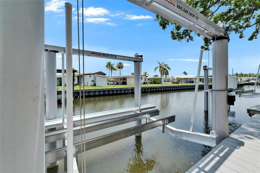 A boat lift structure stands over a canal next to a wooden dock — 6530 SIMONE SHORES CIRCLE, APOLLO BEACH, FL