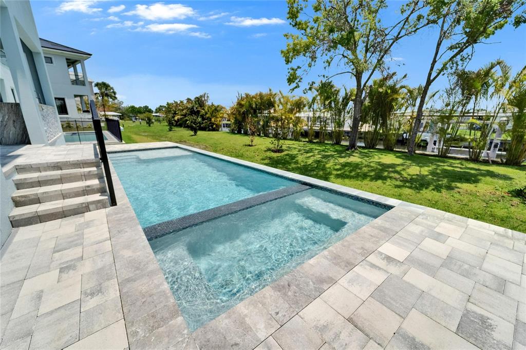 A rectangular swimming pool with an integrated spa sits on a paved patio beside a house — 6530 SIMONE SHORES CIRCLE, APOLLO BEACH, FL