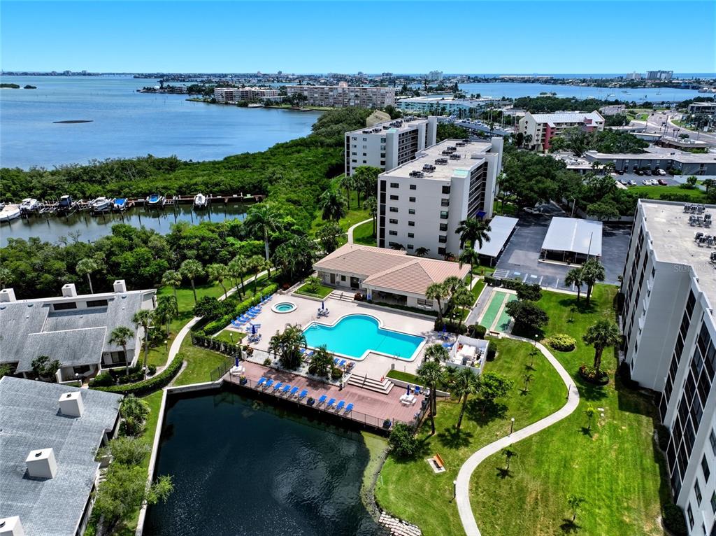 An aerial view shows a swimming pool, a pond, and multi-story apartment buildings — 1328 PASADENA AVENUE S UNIT 308, SOUTH PASADENA, FL