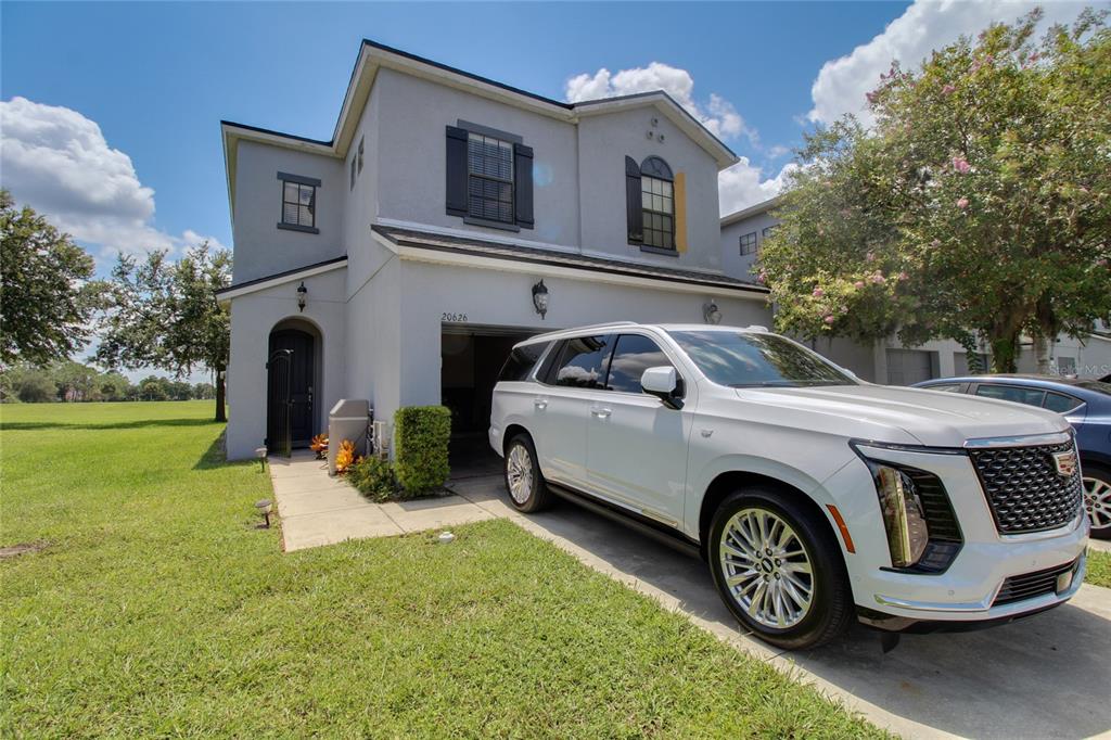 A two-story house with a gray stucco exterior and a white SUV parked in front — 20626 MAXIM PARKWAY, ORLANDO, FL