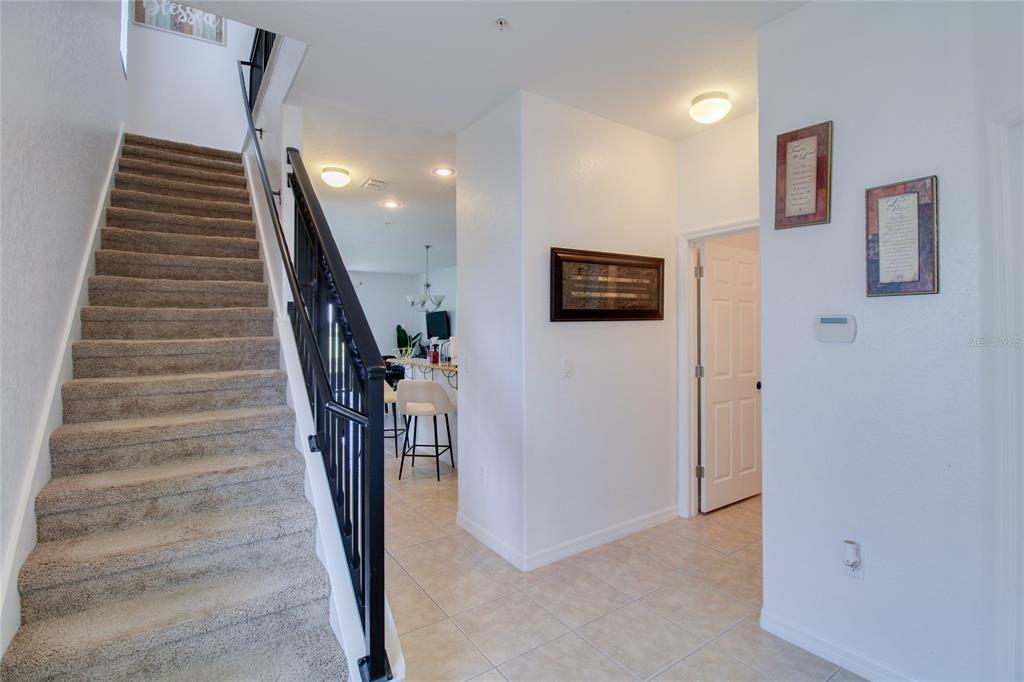 An interior view shows a carpeted staircase, tiled entryway, and a doorway leading to a kitchen — 20626 MAXIM PARKWAY, ORLANDO, FL