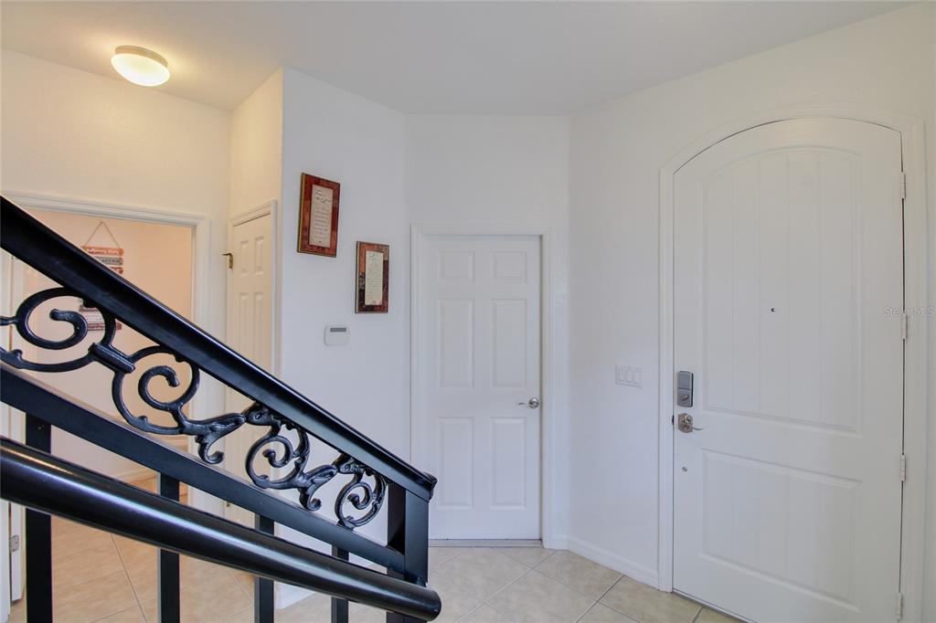 An entryway features a tiled floor, a white arched door, and a black metal staircase railing — 20626 MAXIM PARKWAY, ORLANDO, FL