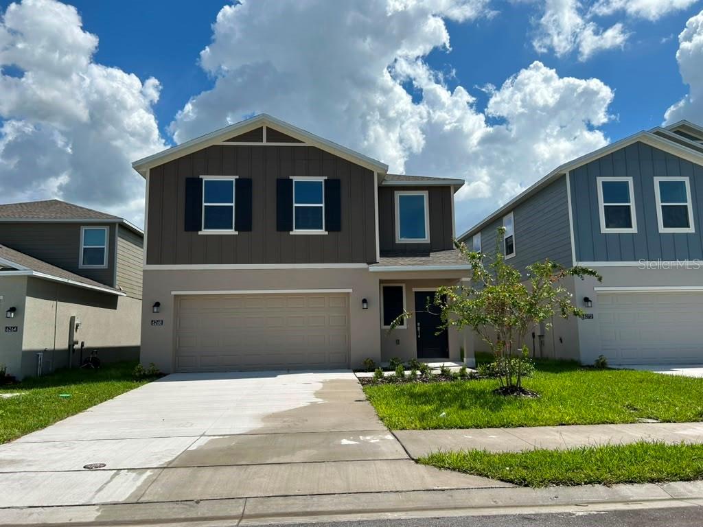 A two-story suburban house features a tan stucco lower level and brown vertical siding above — 6268 BOTTICELLA BOULEVARD, WINTER HAVEN, FL