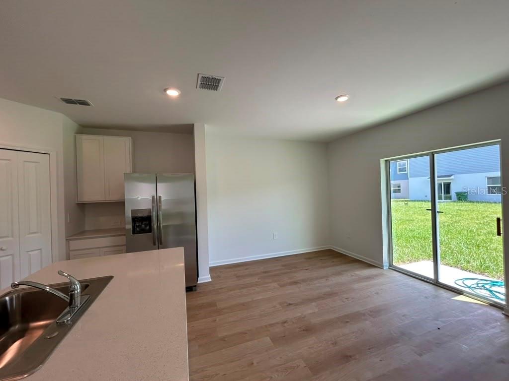 A kitchen with stainless steel appliances, light wood flooring, and a sliding glass door — 6268 BOTTICELLA BOULEVARD, WINTER HAVEN, FL