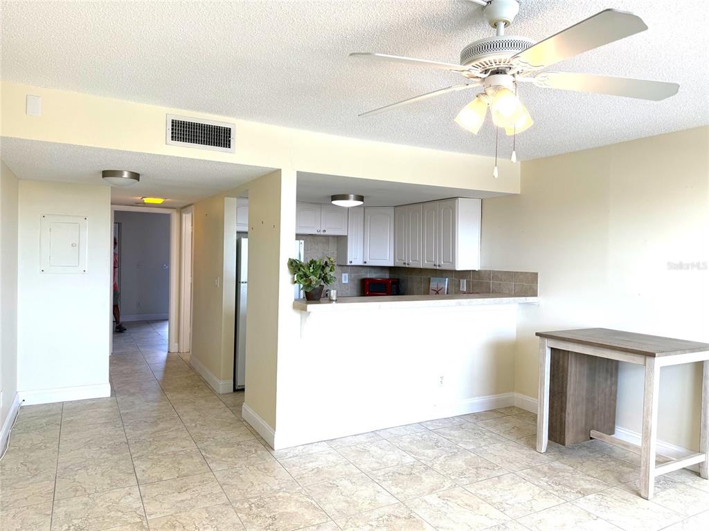A kitchen with white cabinets and a breakfast bar overlooks a tiled living area — 7665 SUN ISLAND DRIVE S UNIT 409, SOUTH PASADENA, FL