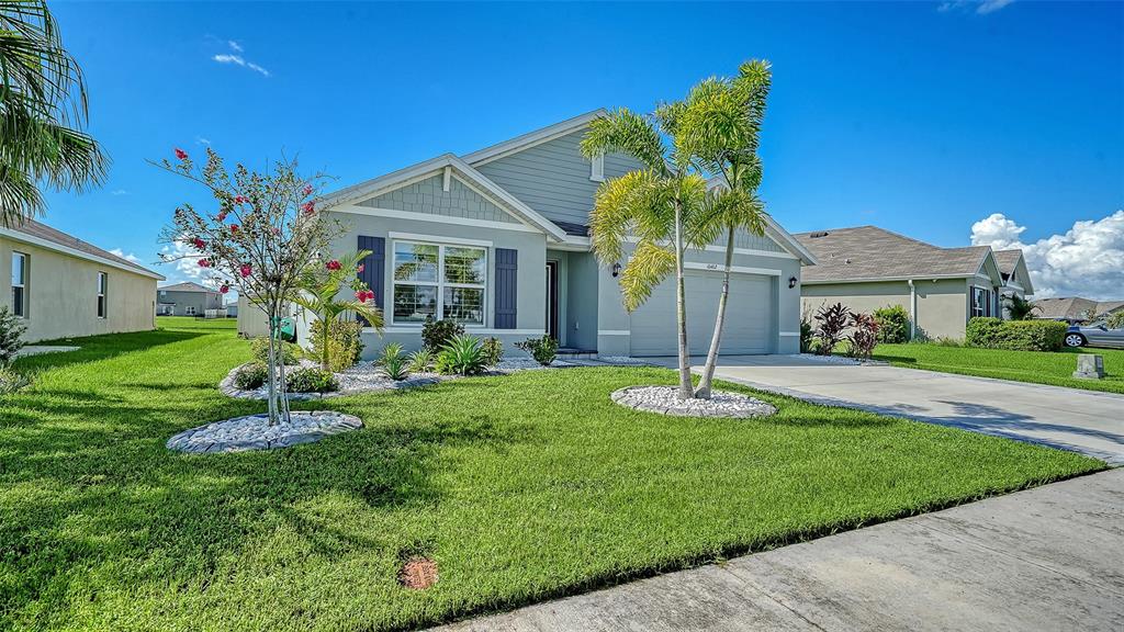 A light blue single-story house features a front lawn, palm trees, and a concrete driveway — 10402 CHARLOTTE DRIVE, PARRISH, FL