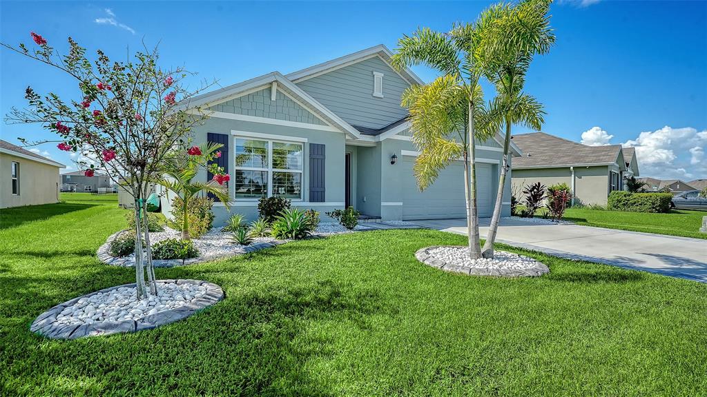 A light blue single-story house with a two-car garage and a landscaped front yard — 10402 CHARLOTTE DRIVE, PARRISH, FL