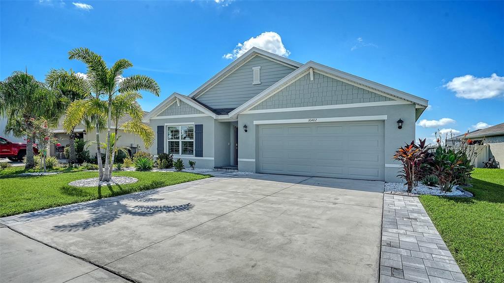 A single-story house with a light blue exterior, a two-car garage, and a paved driveway — 10402 CHARLOTTE DRIVE, PARRISH, FL