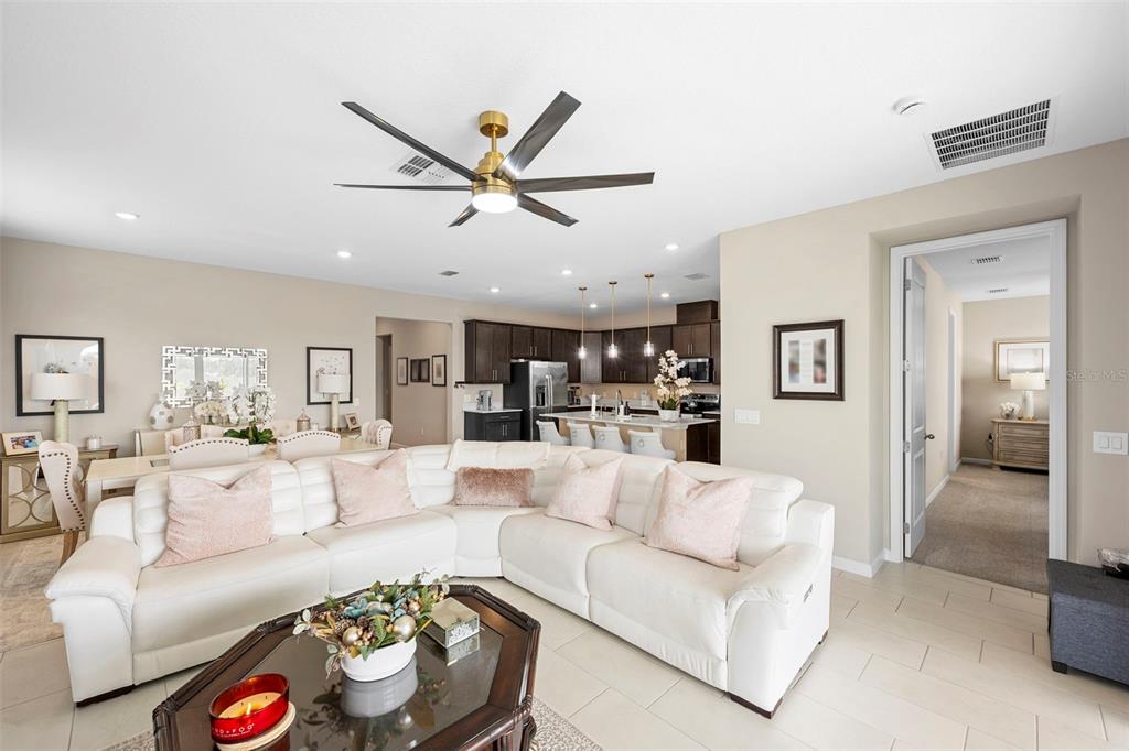 A white sectional sofa sits in a living room open to a kitchen with dark cabinets — 608 HENNEPIN LOOP, LAKE WALES, FL