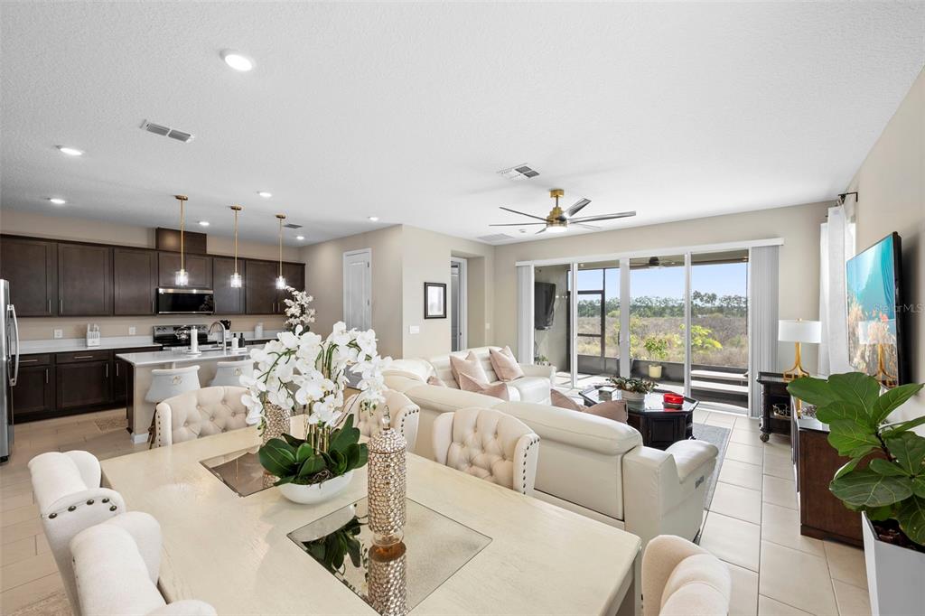 An open-concept living and dining area features a kitchen with dark cabinets and tile flooring — 608 HENNEPIN LOOP, LAKE WALES, FL