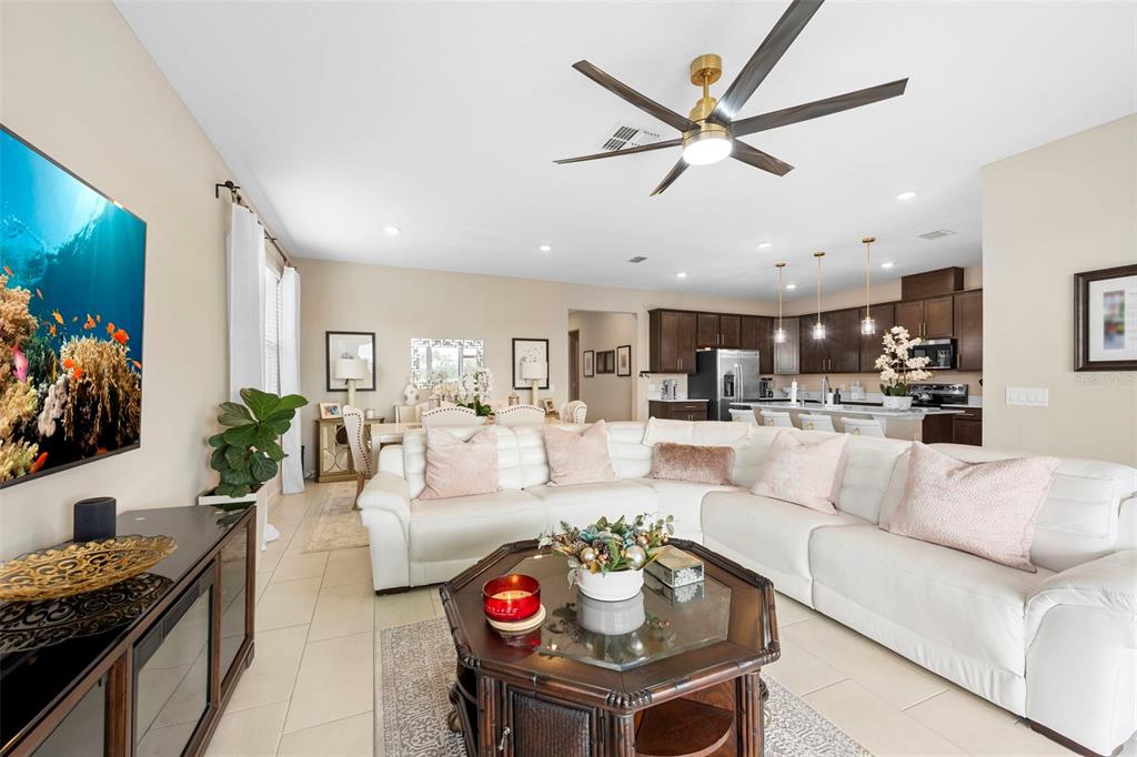 A living room with a white sectional sofa, a glass-topped coffee table, and an open kitchen — 608 HENNEPIN LOOP, LAKE WALES, FL