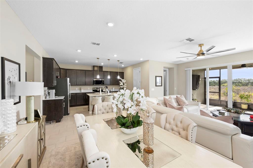 An open-concept living area features a dining space, a kitchen with dark cabinets, and seating — 608 HENNEPIN LOOP, LAKE WALES, FL